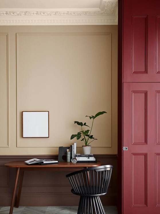 Warm neutral (Castell Pink) home study area with a red (Arras) door next to a wooden desk and chair.