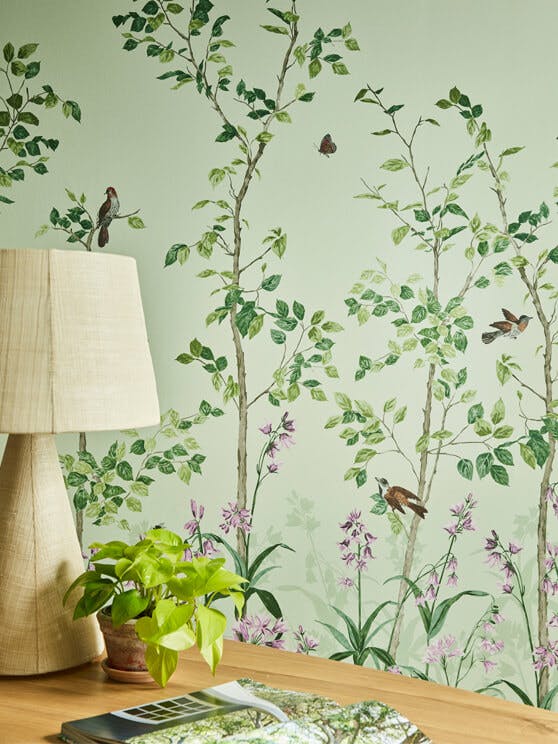 Close-up of National Trust green floral mural wallpaper featuring birds and butterflies (Bird & Bluebell - Pea Green).