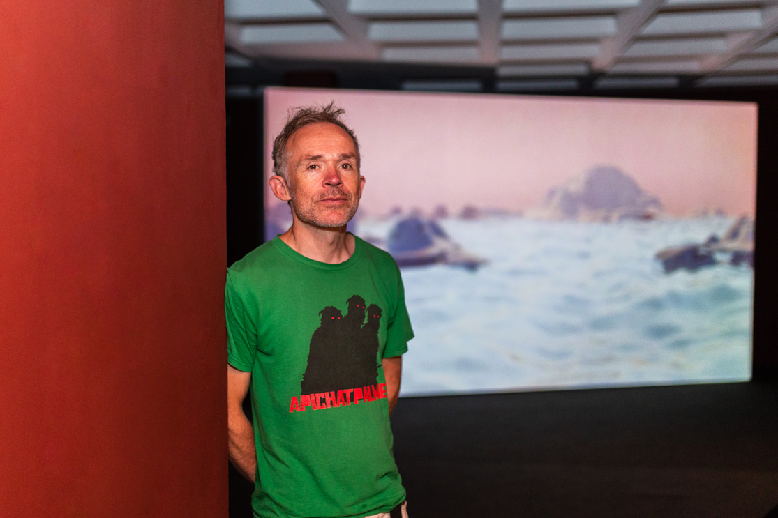 艺术家兼电影制作人本·里弗斯(Ben Rivers)与他的电影《Look Then Below》(2020)合影。墙:挂毯。@lisawhitingphotography