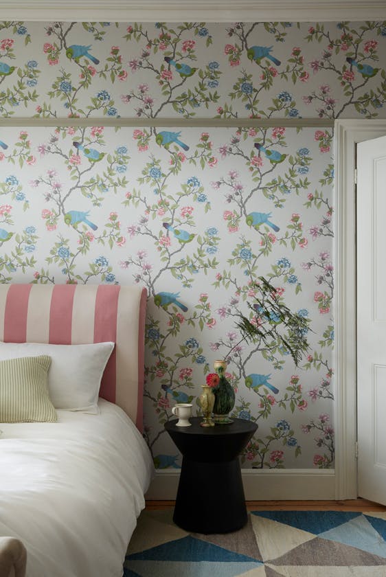 Bedroom featuring grey floral and bird wallpaper (Aderyn - French Grey) with a pink striped bed and sidetable.