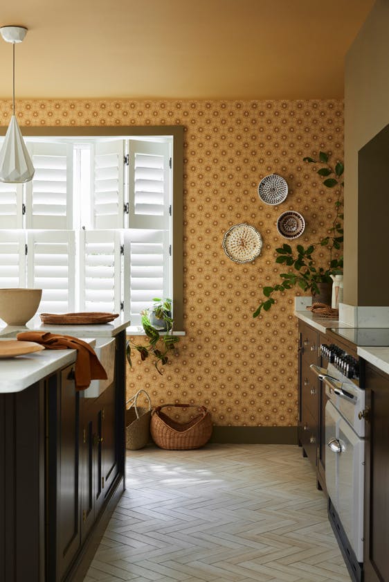 Kitchen space featuring golden yellow small print floral wallpaper (Ditsy Block - Bombolone) with a large window and dark brown cabinets.