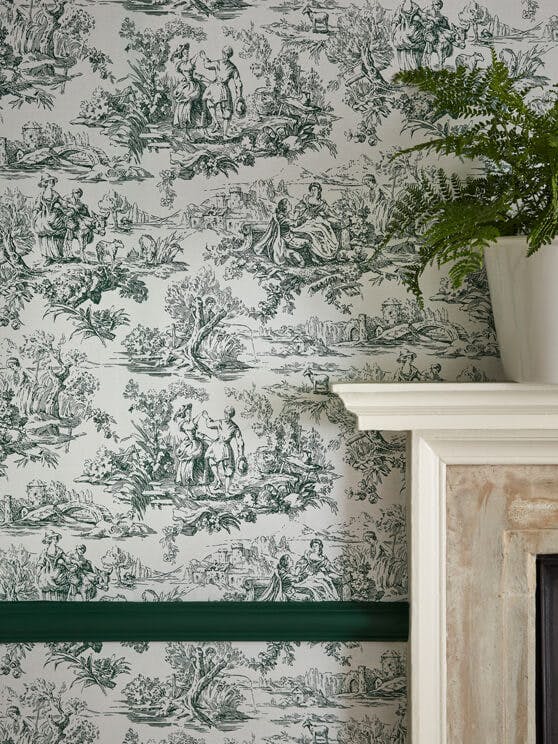 Close-up of National Trust dark green French Toile wallpaper (Lovers' Toile - Puck) and a fireplace surround in the corner.