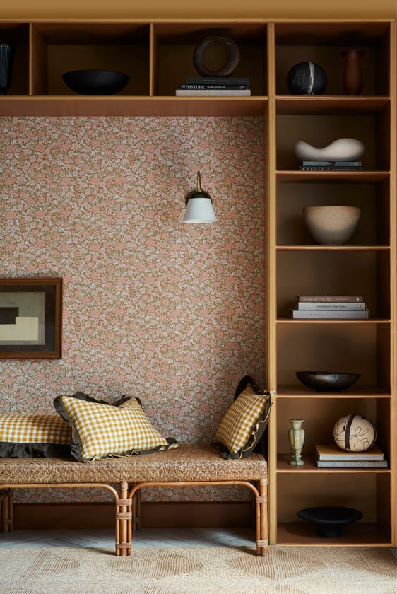 Reading nook featuring ditsy floral wallpaper (Spring Flowers - Bombolone) with shelving surround and a seat with scatter cushions.