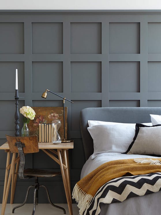 Bedroom featuring a bed with a grey headboard in front of a dark grey paneled wall in 'Scree'.