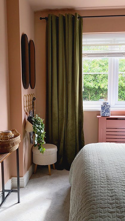 Corner of the Briar Rose - Salix bedroom with pink (Masquerade) walls next to a window with green floor-length curtain.