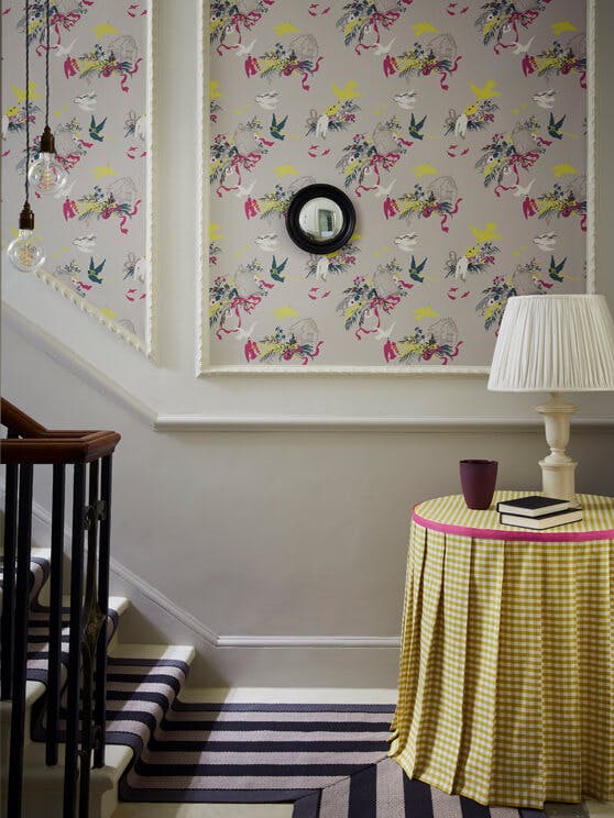 Bottom of stairs with grey bird wallpaper (Volieres - French Grey) and a small table with yellow gingham tablecloth.