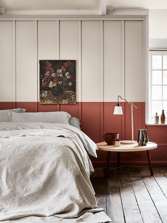 Bedroom with a light grey (French Grey) upper wall and a terracotta red (Tuscan Red) lower wall behind a bed.