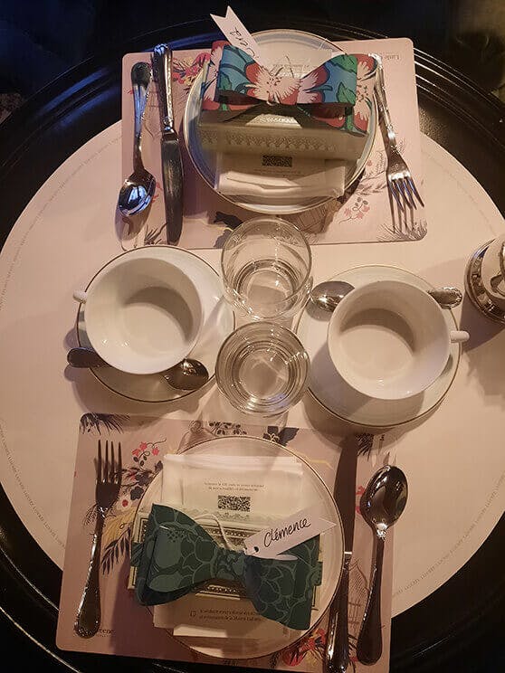 Table setting with floral place mats, white cups and plates, National Trust Papers III inspired decorations and name tags.