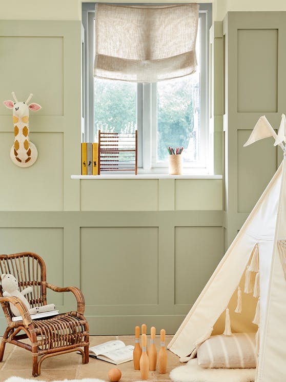 Nursery with an earthy green panelled wall (Green Stone and Green Stone - Light) and a wooden chair and tipi in front.