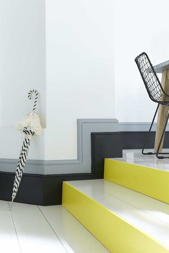 White stairs in a hallway with bright yellow (Trumpet) contrasting stair risers and a black and grey baseboard.