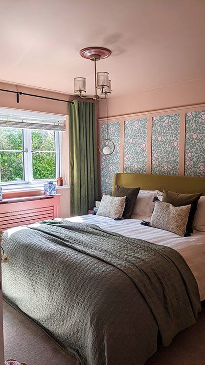 A bedroom with Briar Rose - Salix wallpaper used within pink panelling behind the bed alongside pink walls and ceiling.