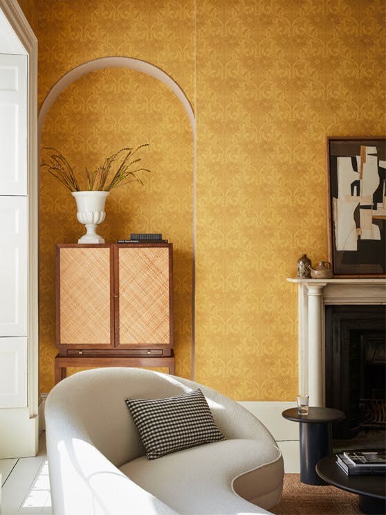 Living room with yellow floral wallpaper (Dahlia Scroll - Giallo) with a chari, cabinet and fireplace.