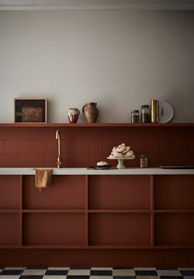 Photograph of a kitchen featuring the rich, deep earth-red paint colour 'Muscovado', alongside 'Slaked Lime - Deep' on the walls.