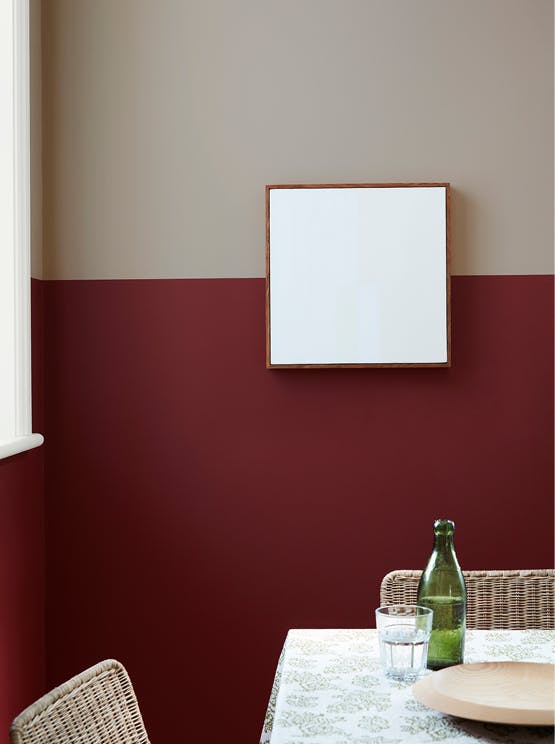 Dining room with upper wall in warm neutral 'Rolling Fog - Dark' and lower wall in deep red 'Arras', with a table and chairs.
