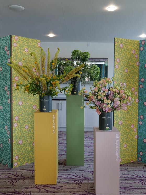 Three stands painted in Yellow-Pink, Garden and Light Peachblossom, holding flowers in black Little Greene paint tins.