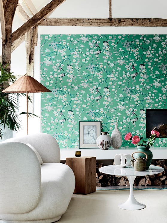 Living area with green printed floral and bird wallpaper (Massingberd Blossom - Verditer), cream sofa and ceiling beams. 