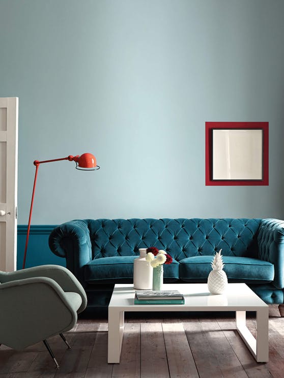 Living room featuring Celestial Blue and Marine Blue walls with a couch, coffee table, armchair and red contrasting accents.