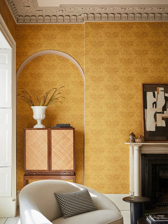 Living room with yellow floral wallpaper (Dahlia Scroll - Giallo) with a chair, cabinet and fireplace.