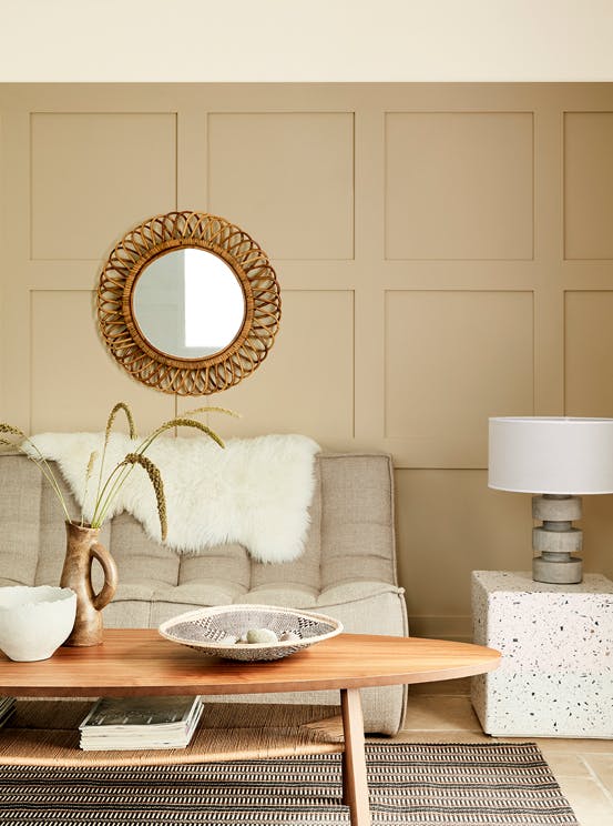 Paneled living space painted in warm neutral 'Travertine' with a sofa and a wooden coffee table.