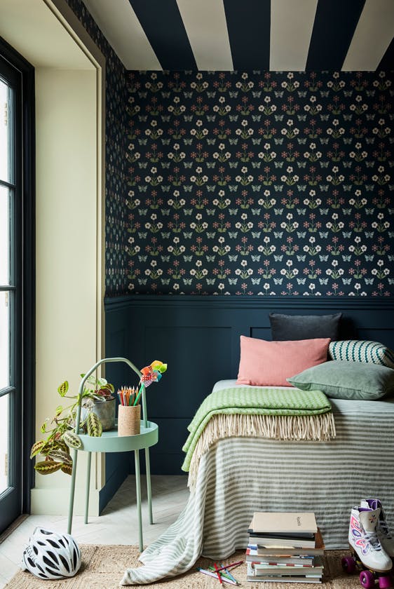 Bedroom featuring dark blue small print wallpaper (Burges Butterfly - Hicks' Blue) with a bed next to a large window and sidetable.