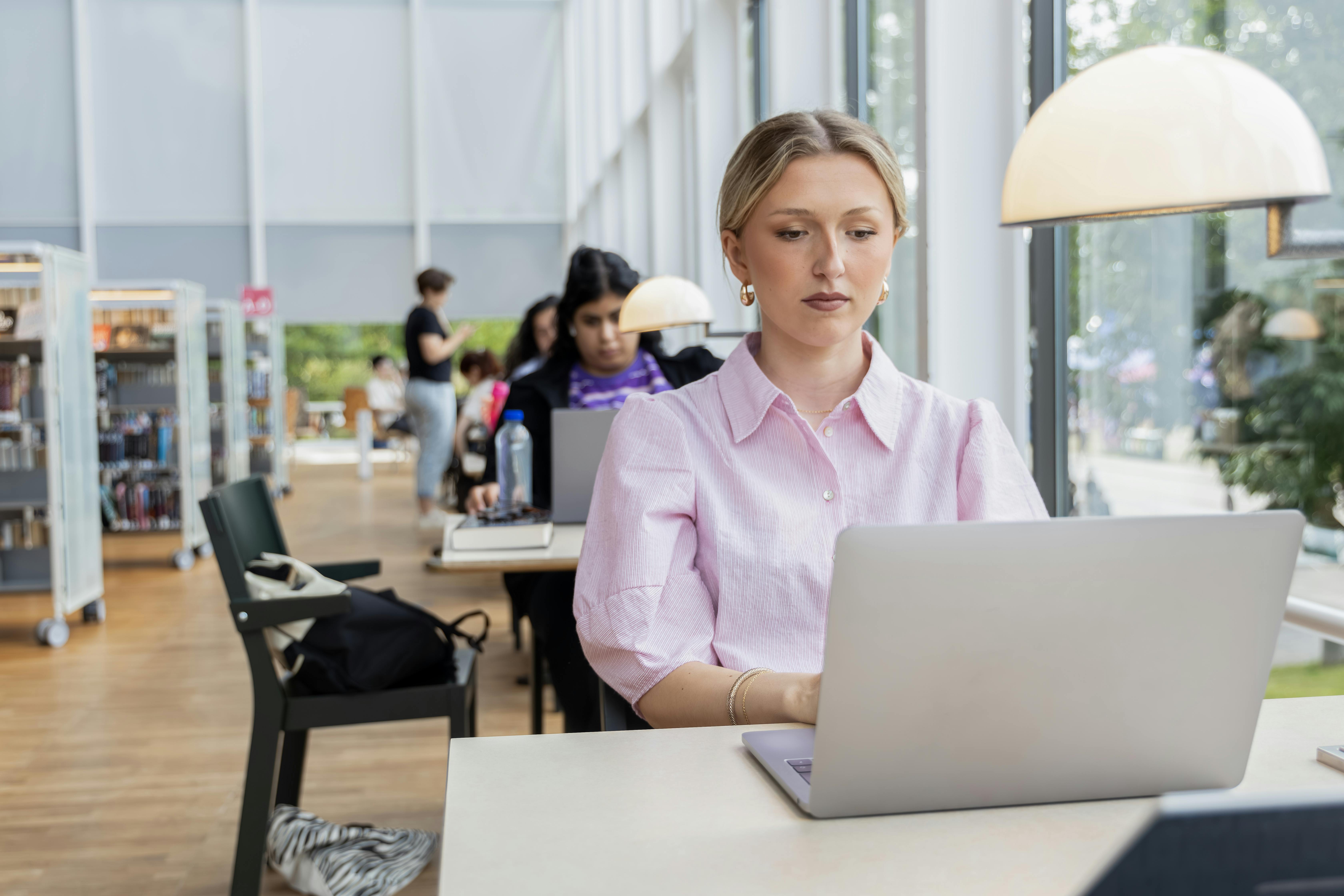 En person, der sidder ved et skrivebord med en bærbar computer