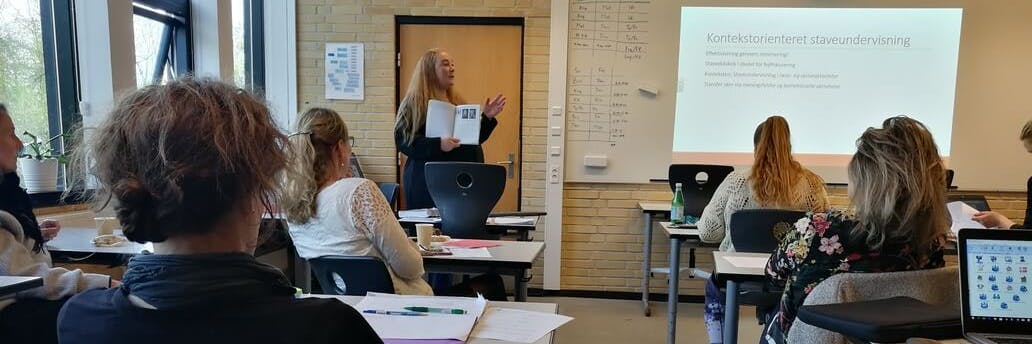 Et klasseværelse med elever og en lærer ved tavlen