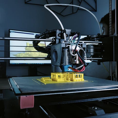 3D printer printing small yellow house. Image Credit: Shutterstock.com/Artshake Media
