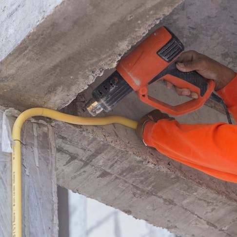 Worker using heat gun to bend electric PVC pipe. Image Credit: Shutterstock.com/BaLL LunLa