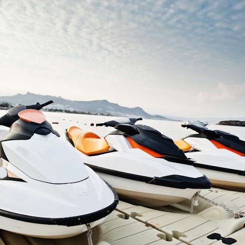 Three jetskis on a dock in front of the ocean