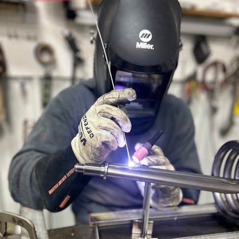 An engineer at Aqua Logic TIG welding titanium fitting to a titanium coil.