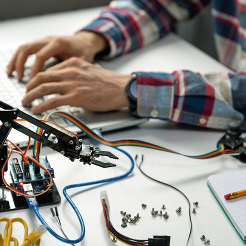 man typing with small robot next to him