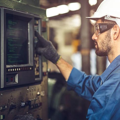 Worker operating a CNC machine with a g-code monitor. Image Credit: Shutterstock.com/Quality Stock Arts