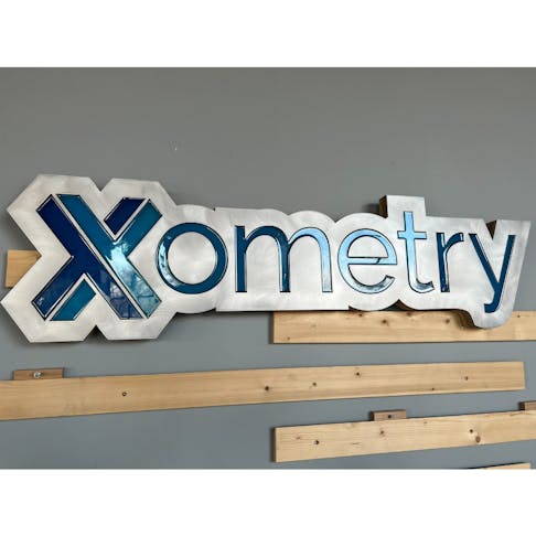 A waterjet cut aluminum "Xometry" sign