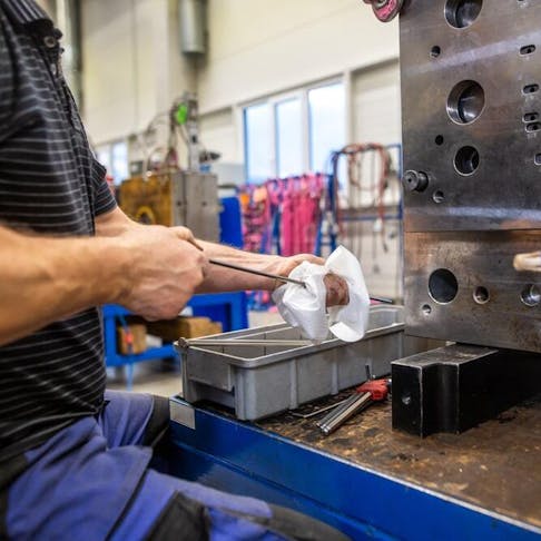 Engineer doing maintenance on the injection mold after production. Image Credit: Simon Kadula/Shutterstock.com