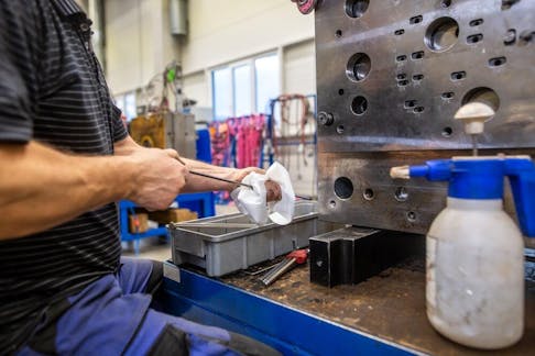 Engineer doing maintenance on the injection mold after production. Image Credit: Simon Kadula/Shutterstock.com