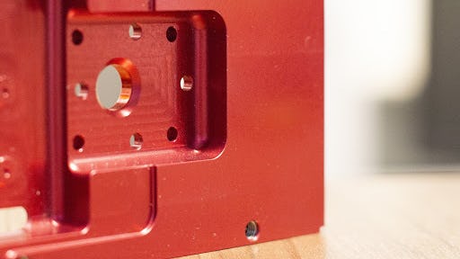 An aluminum CNC machined part with a red anodize finish