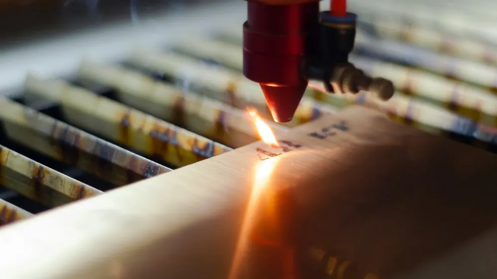 A close-up of a laser engraving machine cutting characters into metal.
