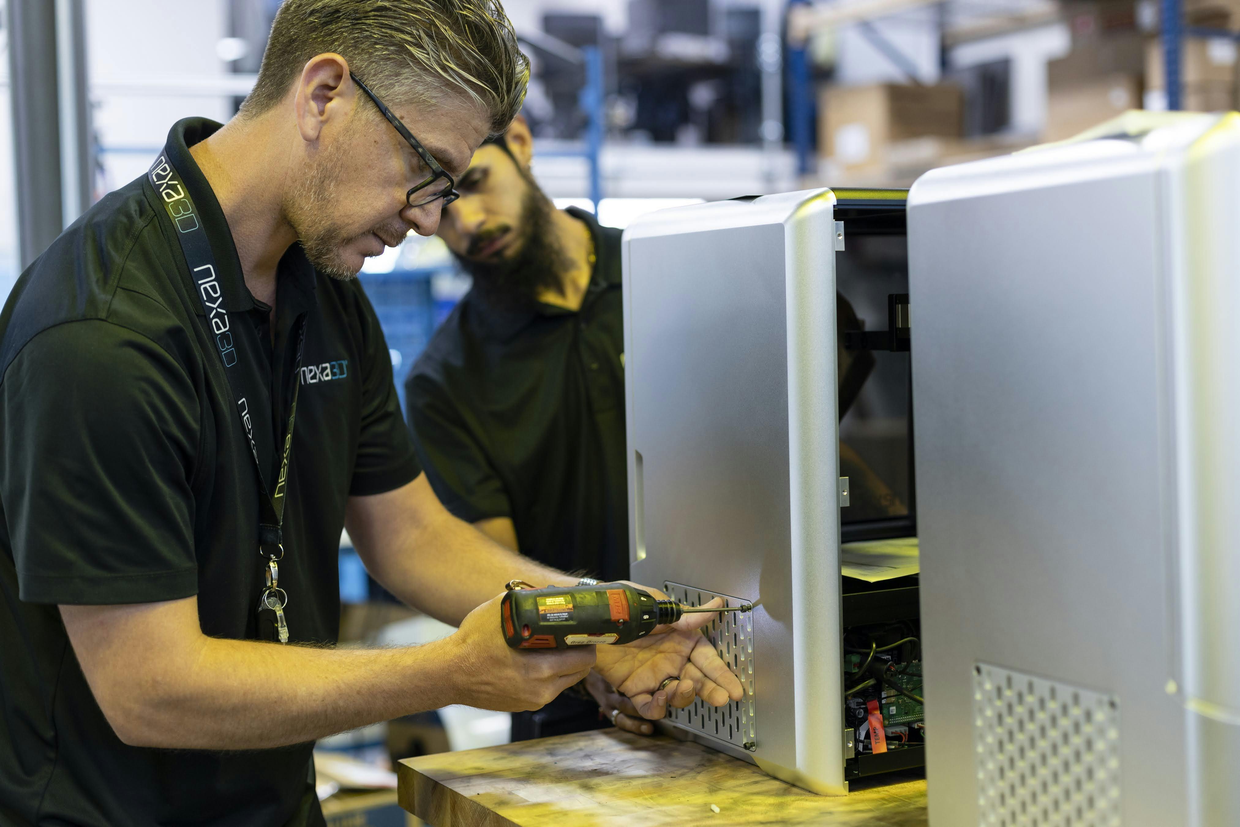a Nexa3D employee drilling a metal part to a XiP 3D printer