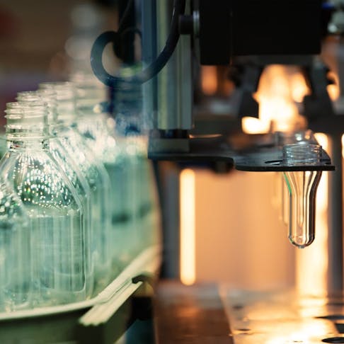 PET bottles being produced in a blow molding machine. Image Credit: MOLPIX/Shutterstock.com