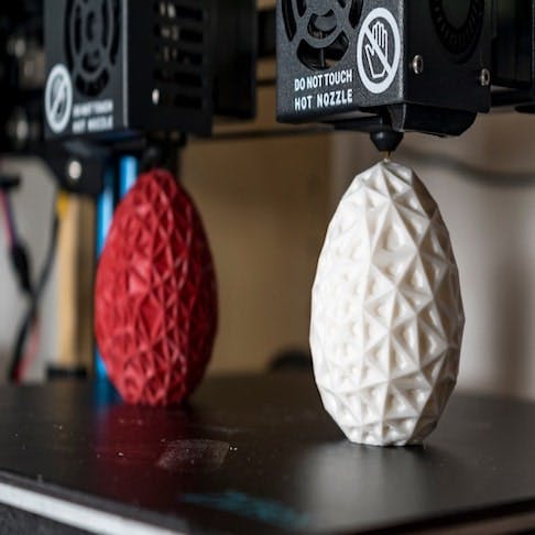 Dual extruder 3d printer producing two bicolor egg model - Image Credit: Shutterstock/Reflexpixel