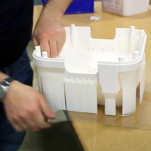 Xometry employee removing support structures from a 3D printed part.