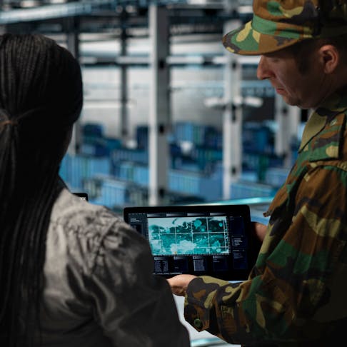 Army personnel watching a test flight on a screen