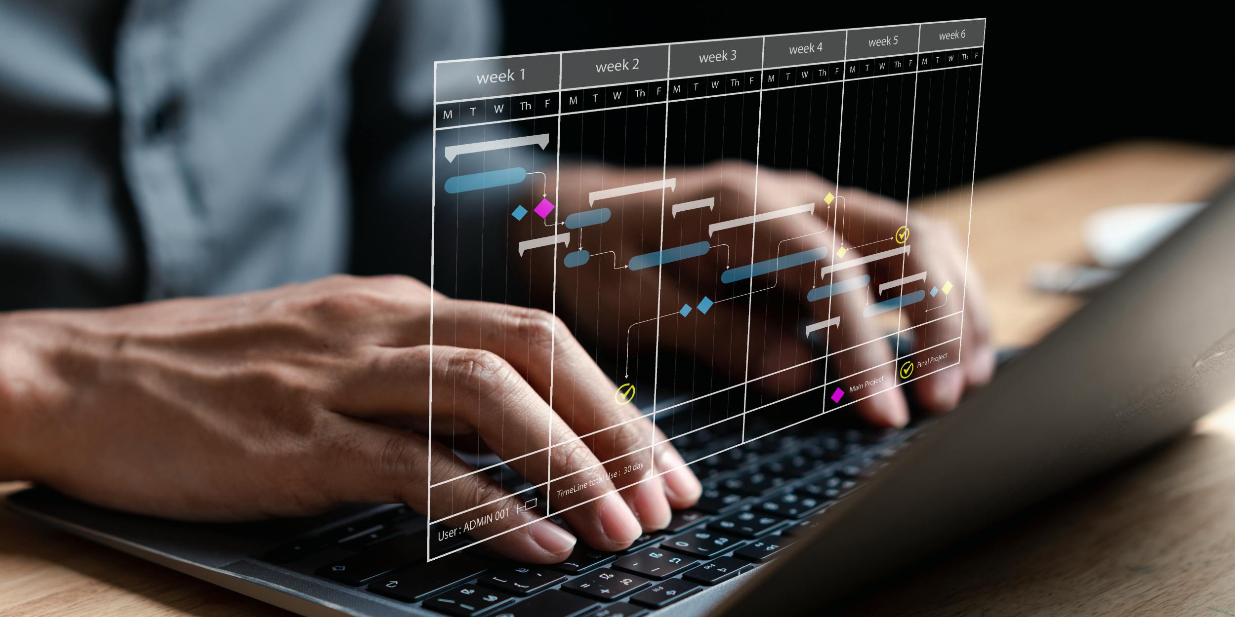 Close-up of hands typing on a laptop displaying a scheduling program