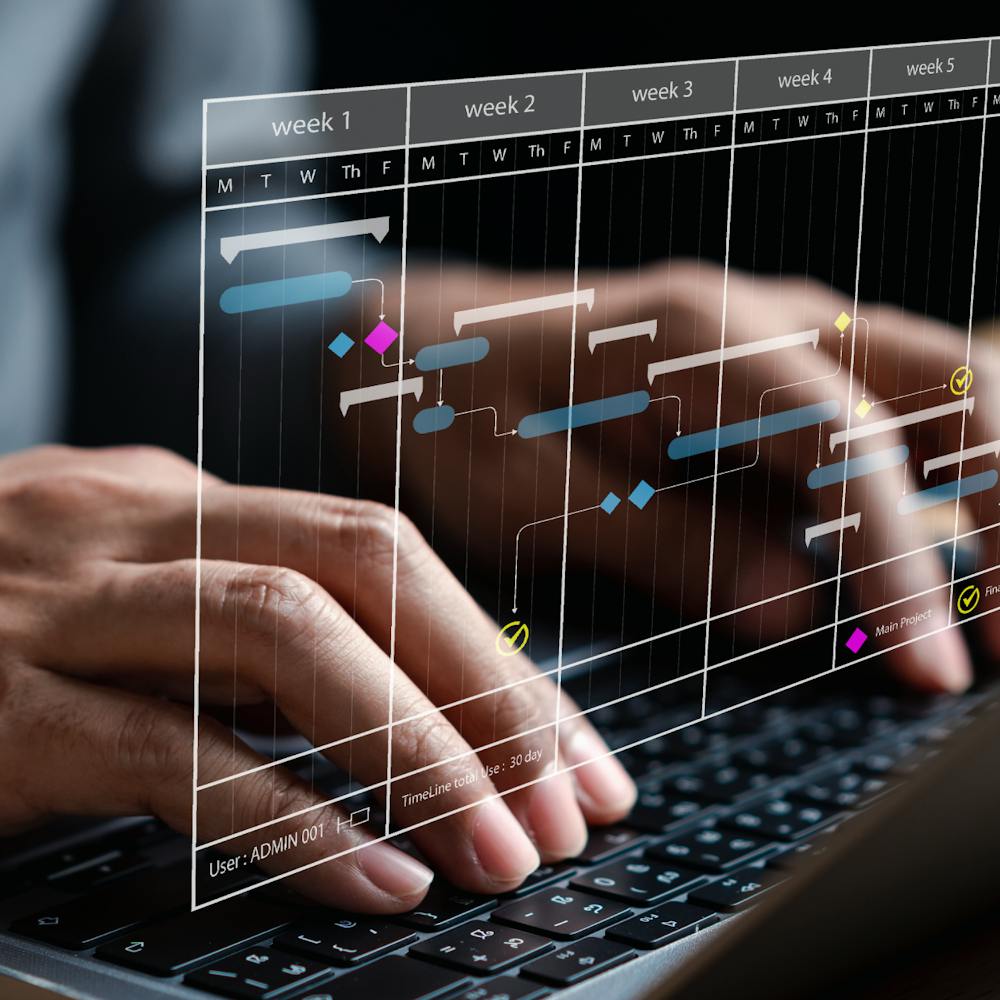 Close-up of hands typing on a laptop displaying a scheduling program
