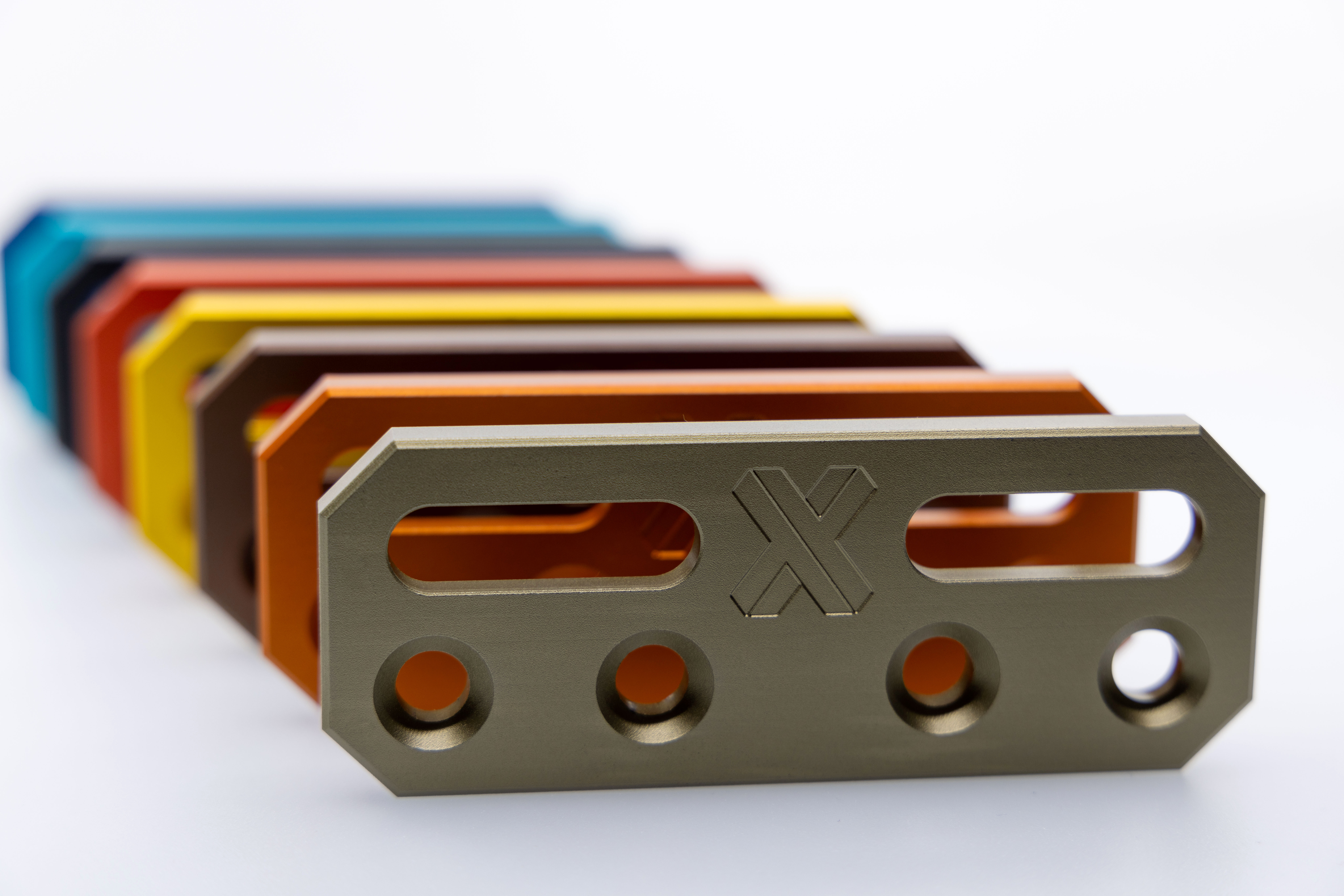 Multiple CNC-machined aluminum parts with different anodized finishes.