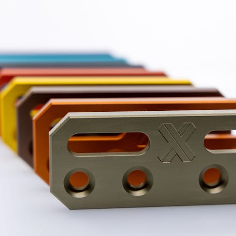 Multiple CNC-machined aluminum parts with different anodized finishes.