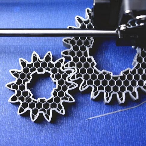 3D printer manufacturing gray gears. Image Credit: Shutterstock.com/R_Boe