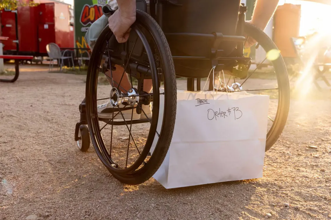 Xometry’s Injection Molding Service Helps Inventor Improve Daily Life for People With Disabilities [Image: Easy Hang hook holding a restaurant takeout bag on the back of a wheelchair]