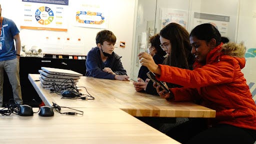 kids crowding together looking at their screens