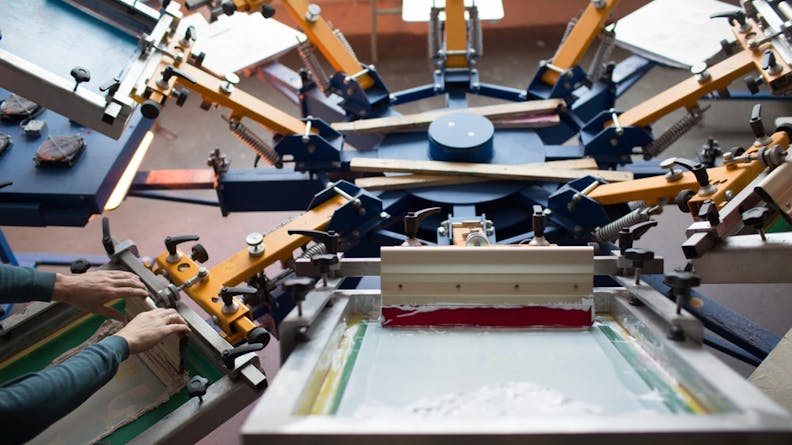 An operator working a silk screen printer.